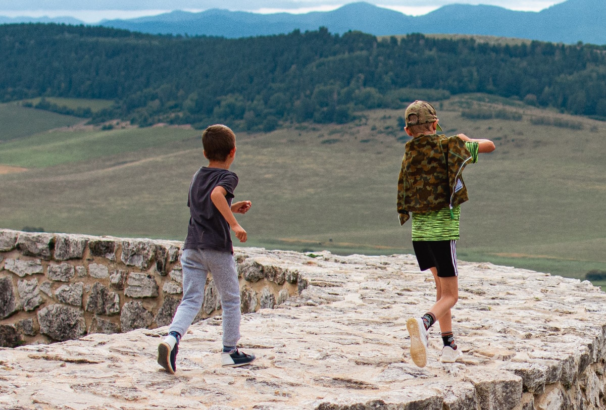 2 Kinder rennen auf einer Mauer